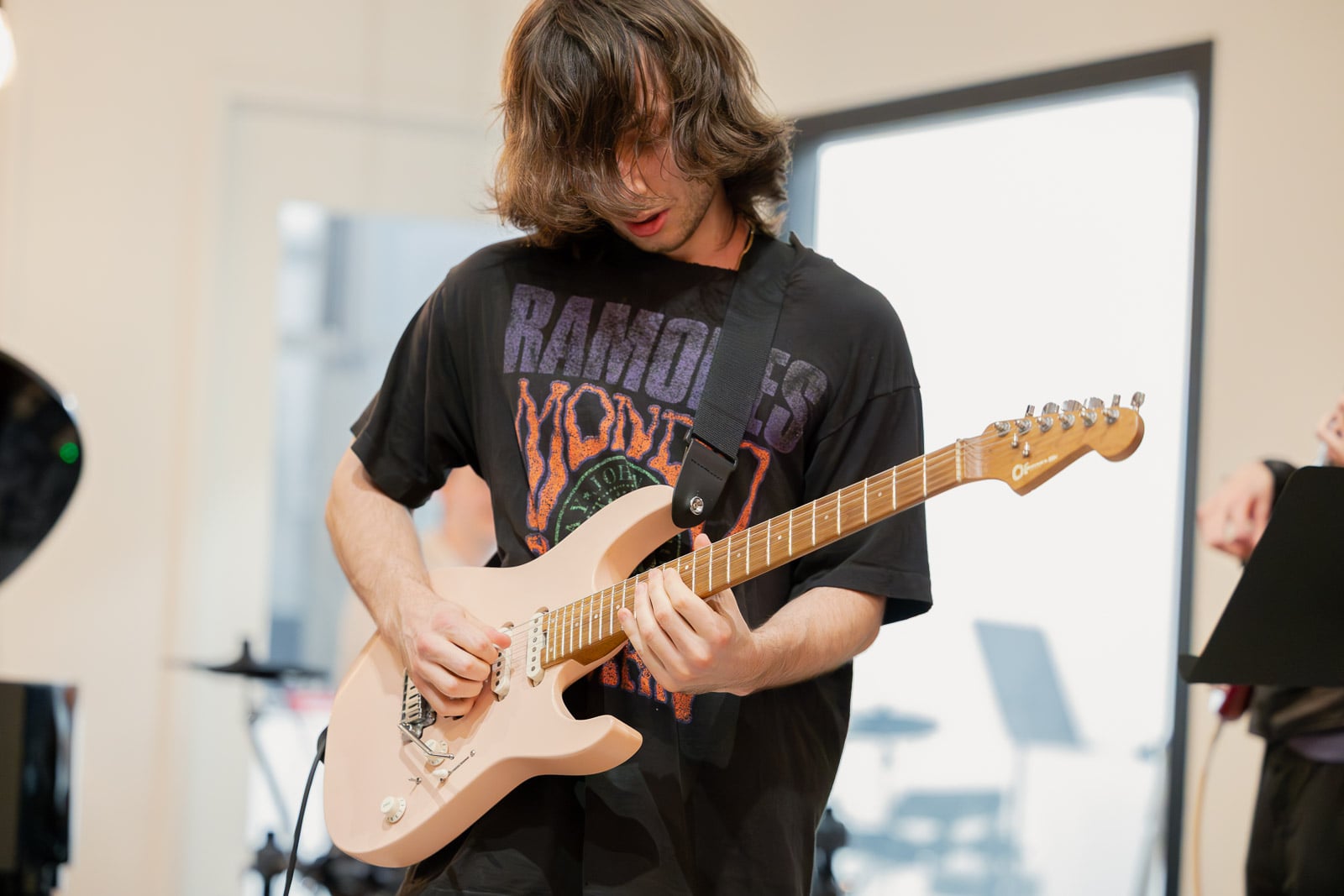 Adult guitarist playing alongside a drummer in the band room at 33 West Street in Downtown Crossing
