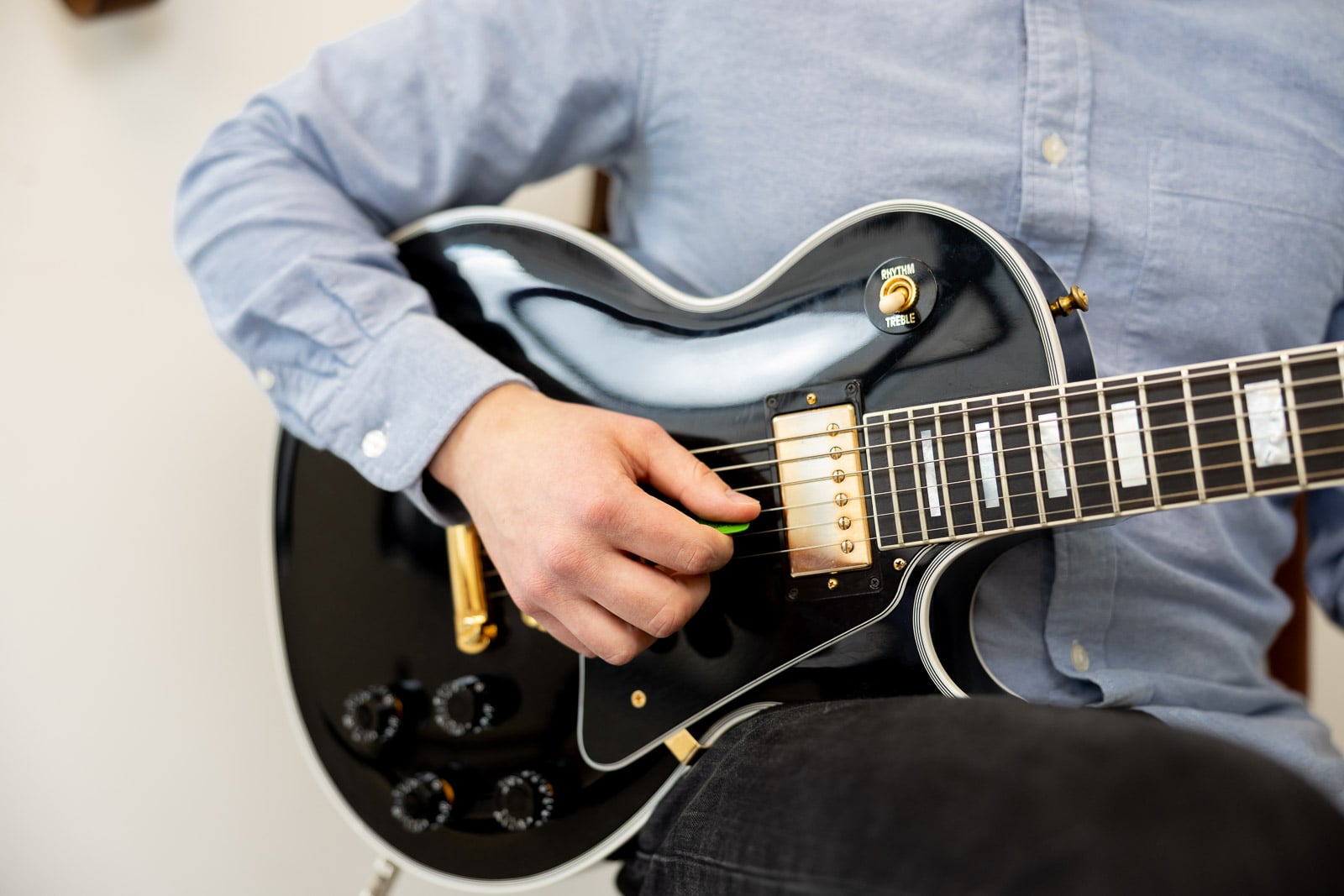 Close up of an adult guitar student fretting a chord on an electric guitar